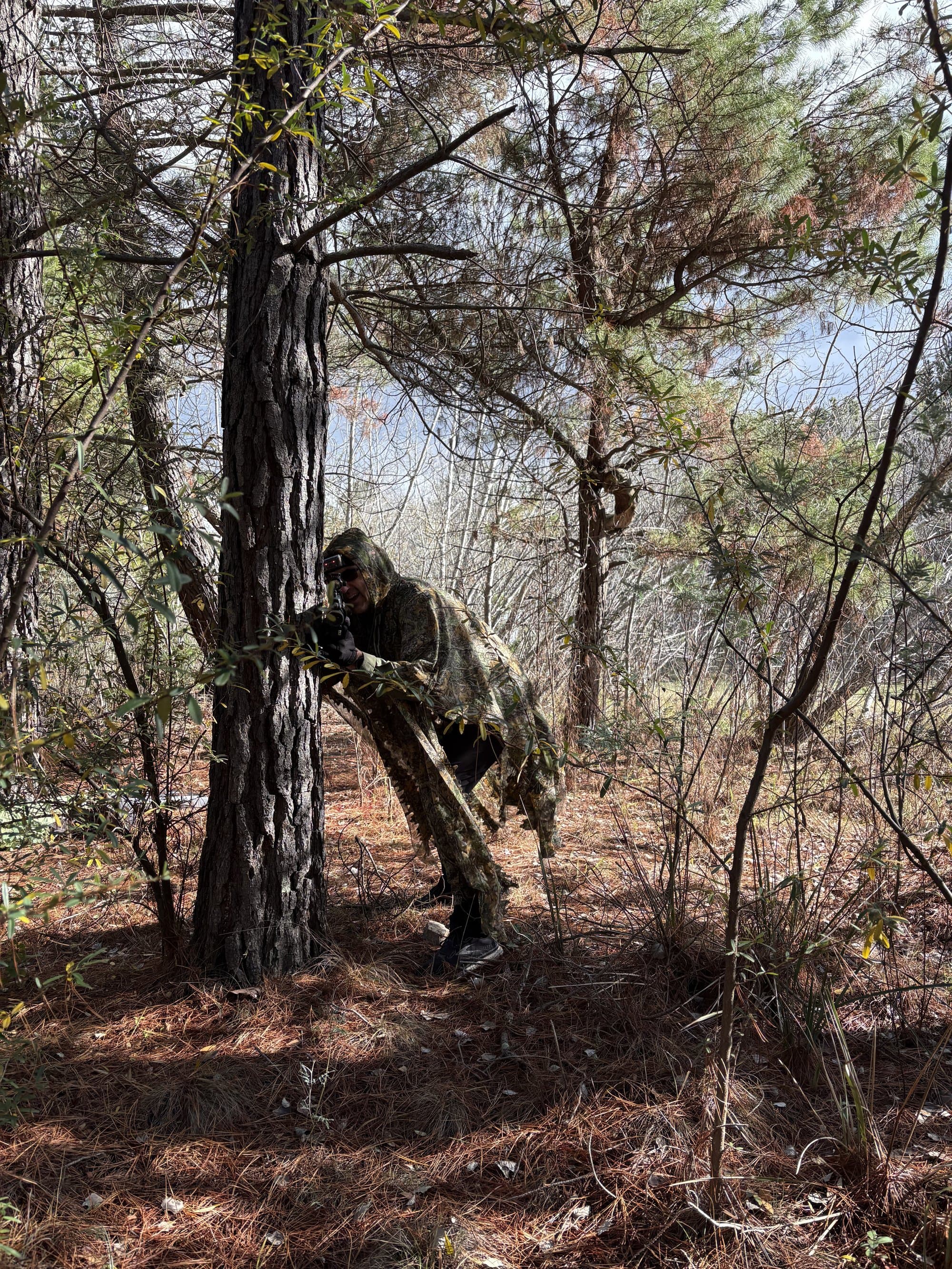 Player in ghillie suit concealed in the pine forest at Fadden Pines