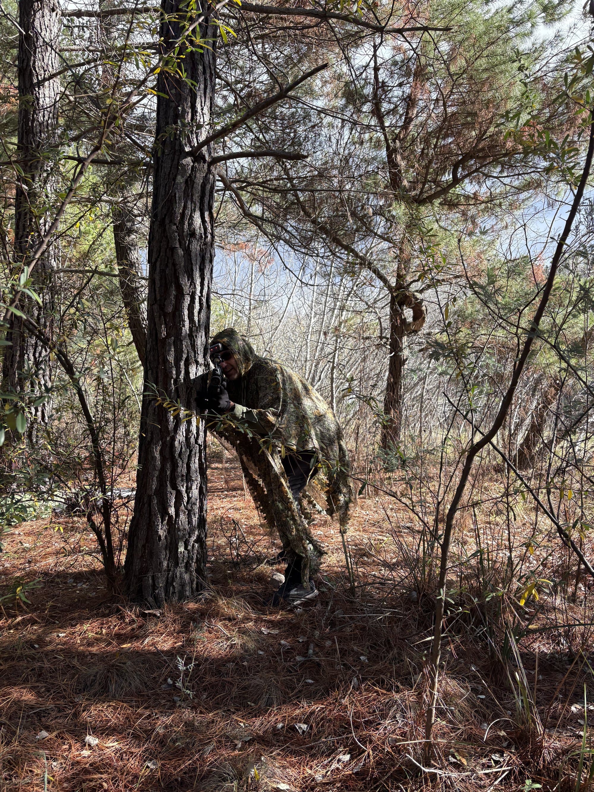 Player in ghillie suit in the pine forest
